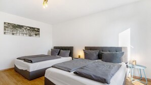 Habitación de hotel con dos camas, una mesita de noche, una lámpara y un cuadro en la pared.