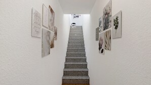 Una scala con opere d'arte alle pareti, che conduce a una zona di riposo con una poltrona.