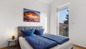 Una camera da letto con un letto, un comodino, un quadro e una finestra.