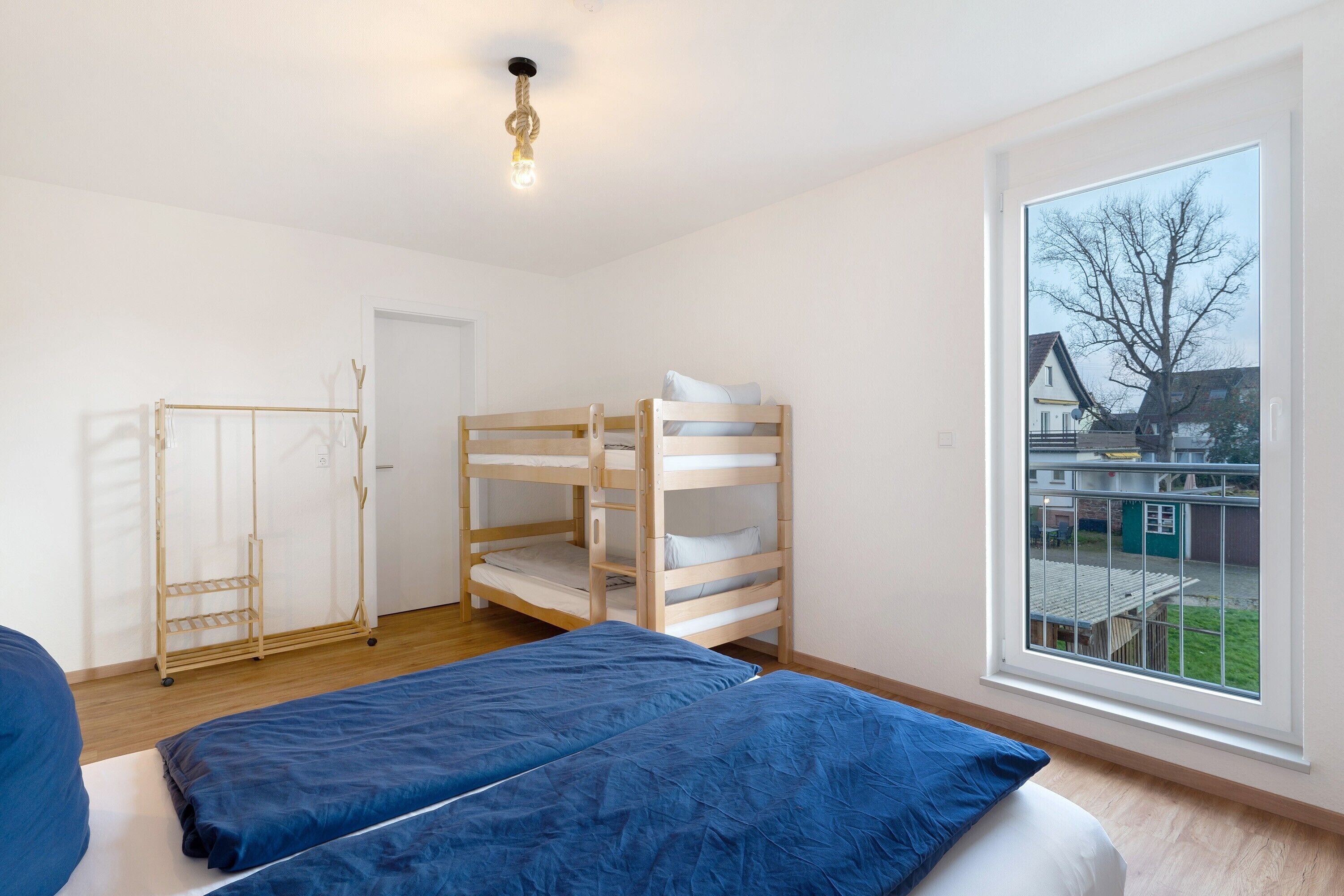 A room with bunk beds, a wardrobe, a window with a view, and a hanging light fixture.