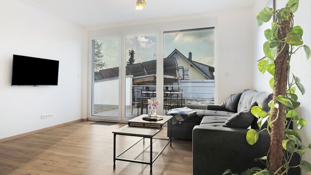 A modern living room with a sofa, a coffee table, and a TV mounted on the wall.