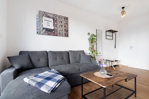 Un salon moderne avec un canapé gris, une table basse en bois et une citation encadrée accrochée au mur.