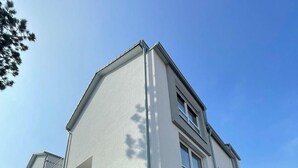 A modern two-story building with a flat roof, large windows, and a balcony.