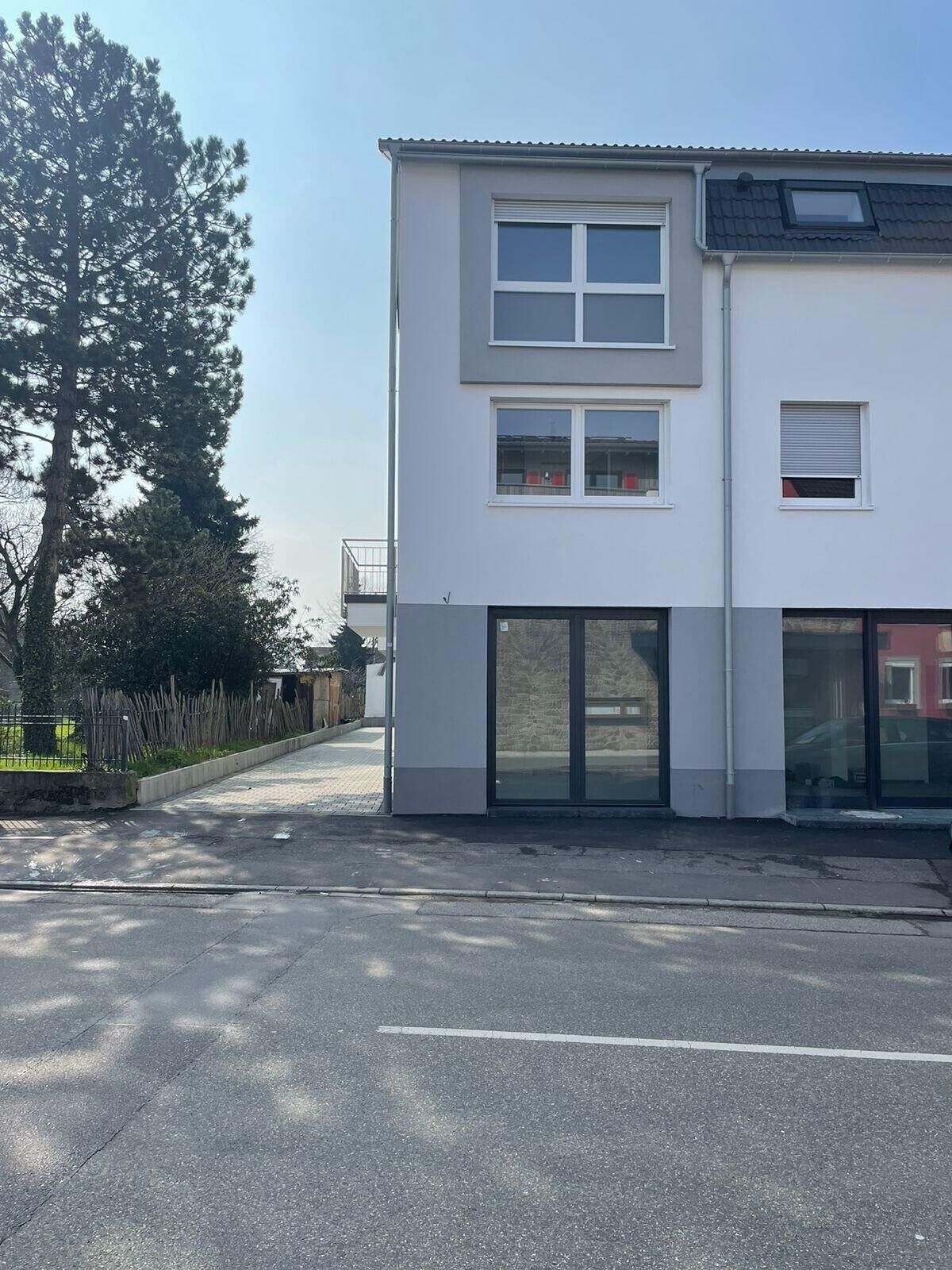 Ein modernes, zweistöckiges Gebäude mit Flachdach, großen Fenstern und einem Glastür-Eingang.