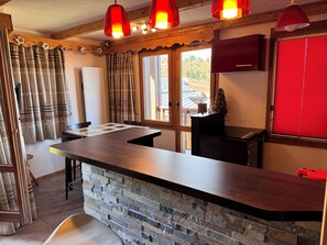 Eine Küche mit einer Steinarbeitsplatte, Holzbalken an der Decke und roten Pendelleuchten.