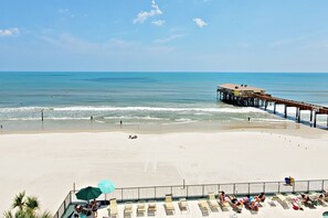 Uma praia com um píer, espreguiçadeiras e guarda-sóis.
