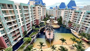 A resort with multiple high-rise buildings, a central water feature, and a sandy beach area. - Grande Carribean Condo By Thita (Pattaya)