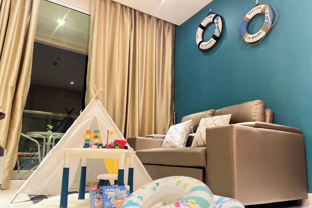 A living room with a beige sofa, a white play tent, children's toys, and two life rings on the wall.