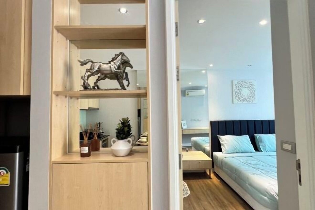 A modern bedroom with a bed, bedside table, and a decorative horse sculpture on a shelf.