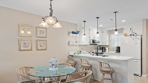 A modern kitchen with a central island, white cabinetry, and pendant lighting. - STEPS to Beach! 2B/2B, Sleeps 9! Beach, POOL, Repeat! NEW! Grill! Wagon! (Panama City Beach)