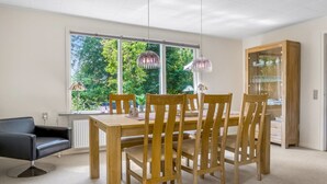 A dining area with a wooden table and chairs, a black sofa, and a glass cabinet with dishes.