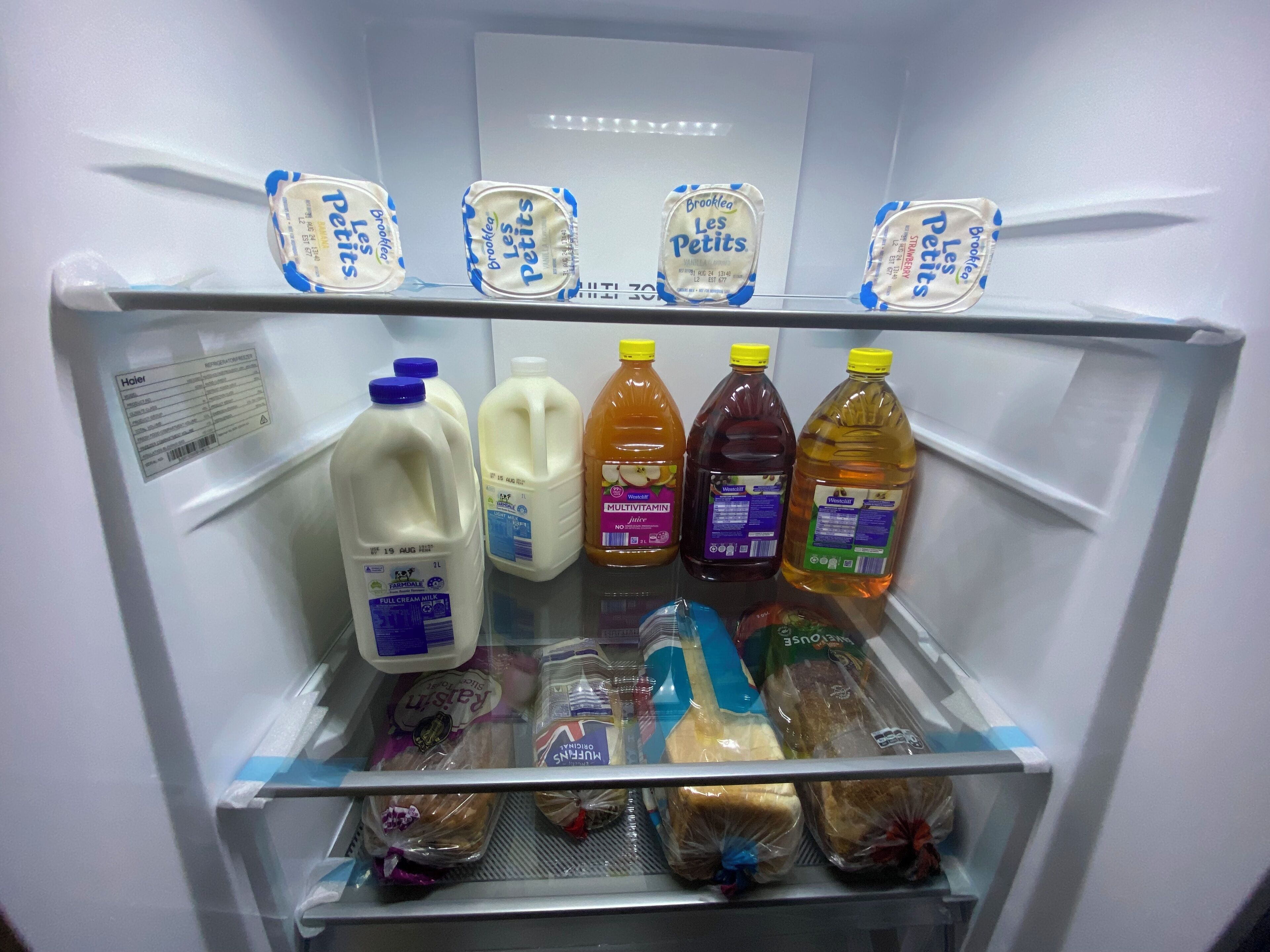 Ein gut gefüllter Kühlschrank mit Lebensmitteln wie Milch, Saft und Brot.