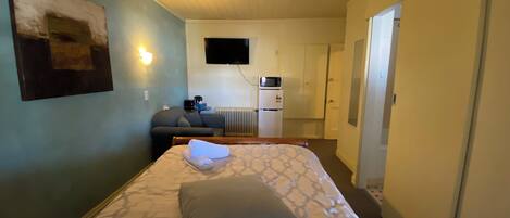 Une chambre d’hôtel équipée d’un lit, d’un canapé, d’une télévision, d’un four à micro-ondes et d’un réfrigérateur.