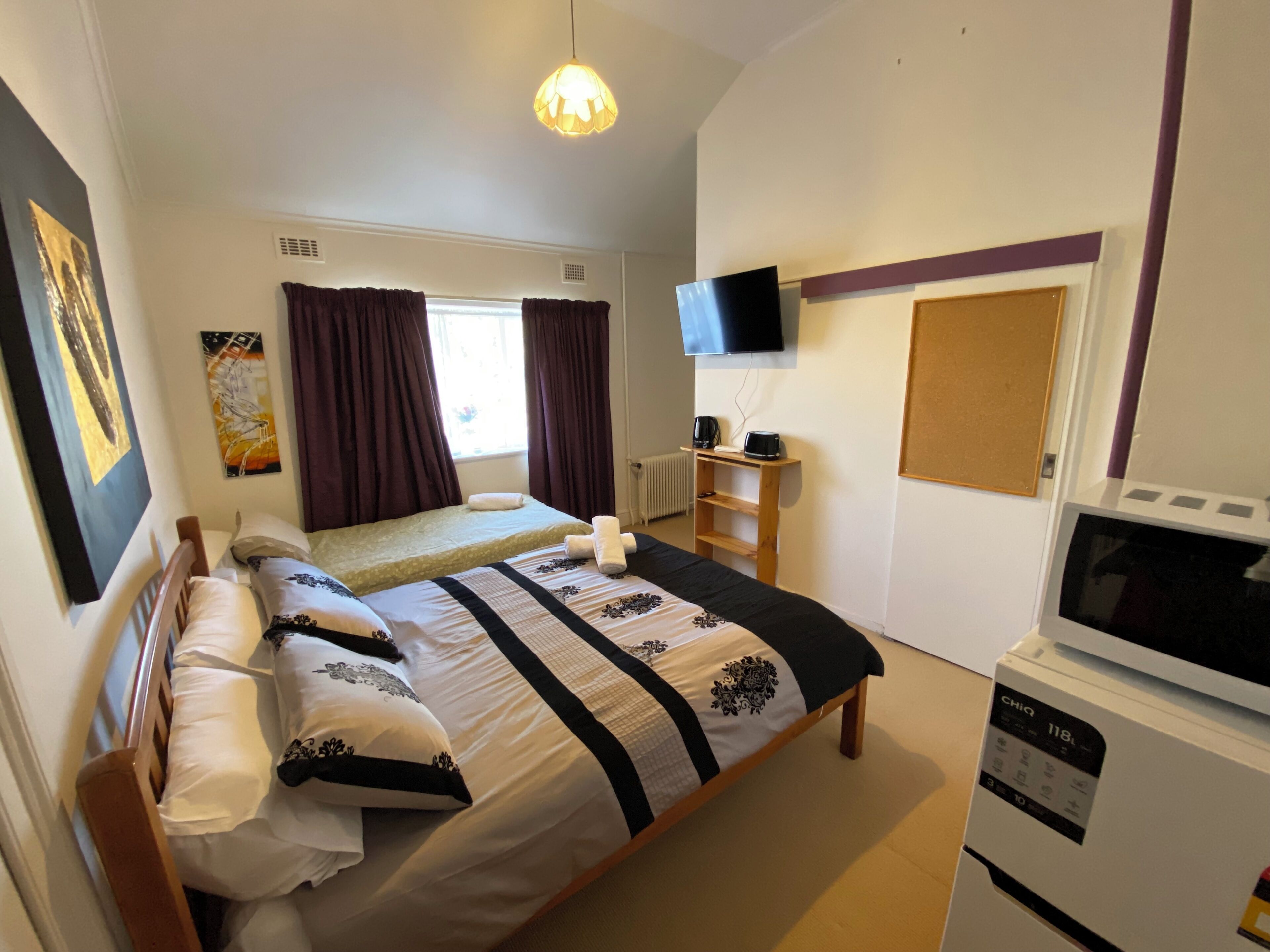 Ein Schlafzimmer mit Bett, Fernseher, Kaffeemaschine und Mikrowelle.