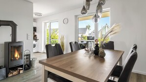 Une cuisine moderne équipée d’un poêle à bois, d’une table à manger, de chaises et offrant une vue sur l’extérieur.