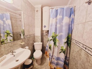 A bathroom with a white sink, toilet, and shower curtain with a tropical print.
