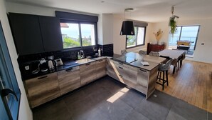 Een moderne keuken met een groot eiland, donkere kasten en uitzicht op zee.