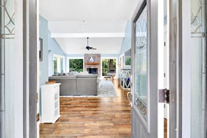 A modern interior with a wooden floor, a grey sofa, a fireplace, and a ceiling fan. - Pet-Friendly Palmetto Dunes House Walk to Beach & (Hilton Head Island)