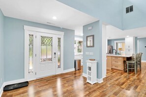 A spacious kitchen with wooden flooring, white cabinetry, and a dining area with chairs. - Pet-Friendly Palmetto Dunes House Walk to Beach & (Hilton Head Island)