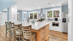 A modern kitchen with a large island, white cabinetry, and a view of the outdoors through large windows. - Pet-Friendly Palmetto Dunes House Walk to Beach & Golf (Hilton Head Island)
