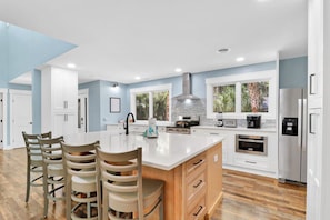 A modern kitchen with a central island, white cabinetry, and a large window providing natural light.