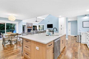 A spacious kitchen with a large island, wooden cabinets, and a built-in dishwasher.