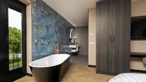 A modern bathroom with a freestanding bathtub, a large mirror, and a vanity with a sink. - Hotel Twenty-Three Amsterdam Airport (Hoofddorp)