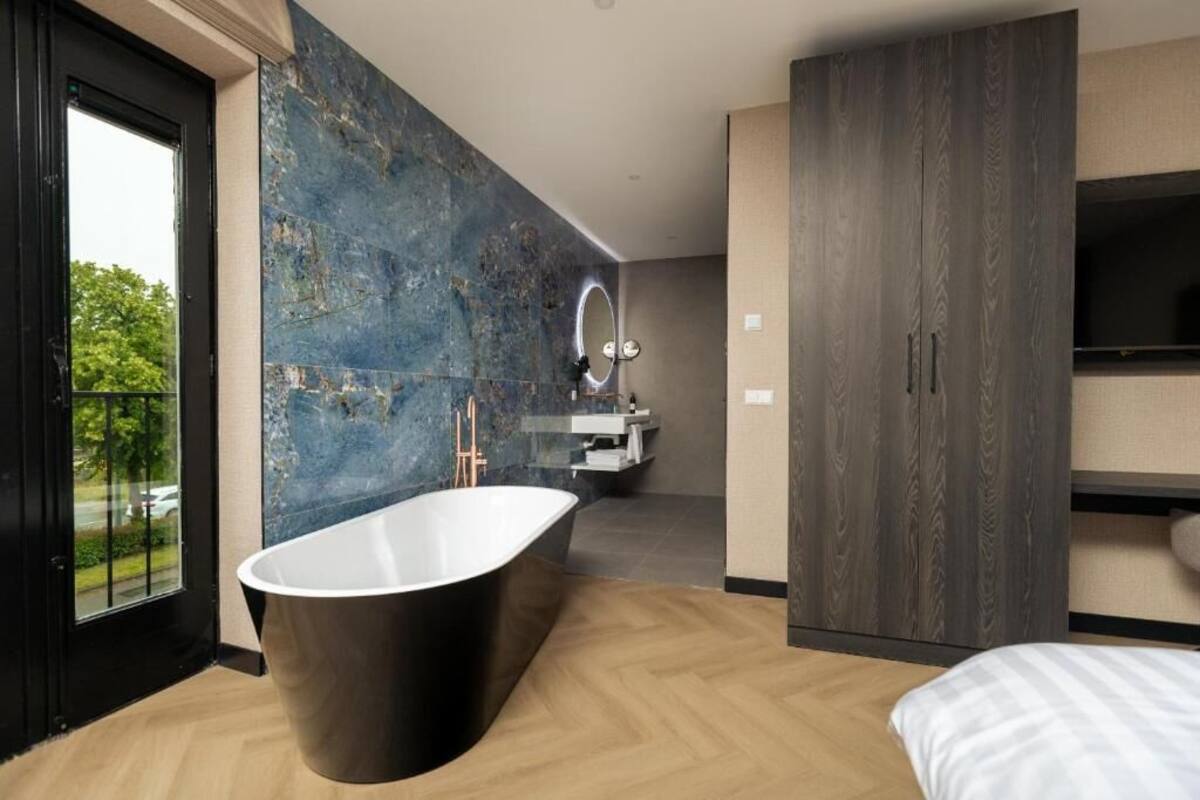 A modern bathroom with a freestanding bathtub, a large mirror, and a vanity with a sink.