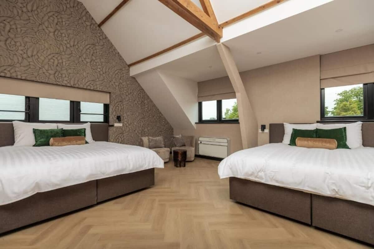 A bedroom with two beds, a small table, and a radiator.