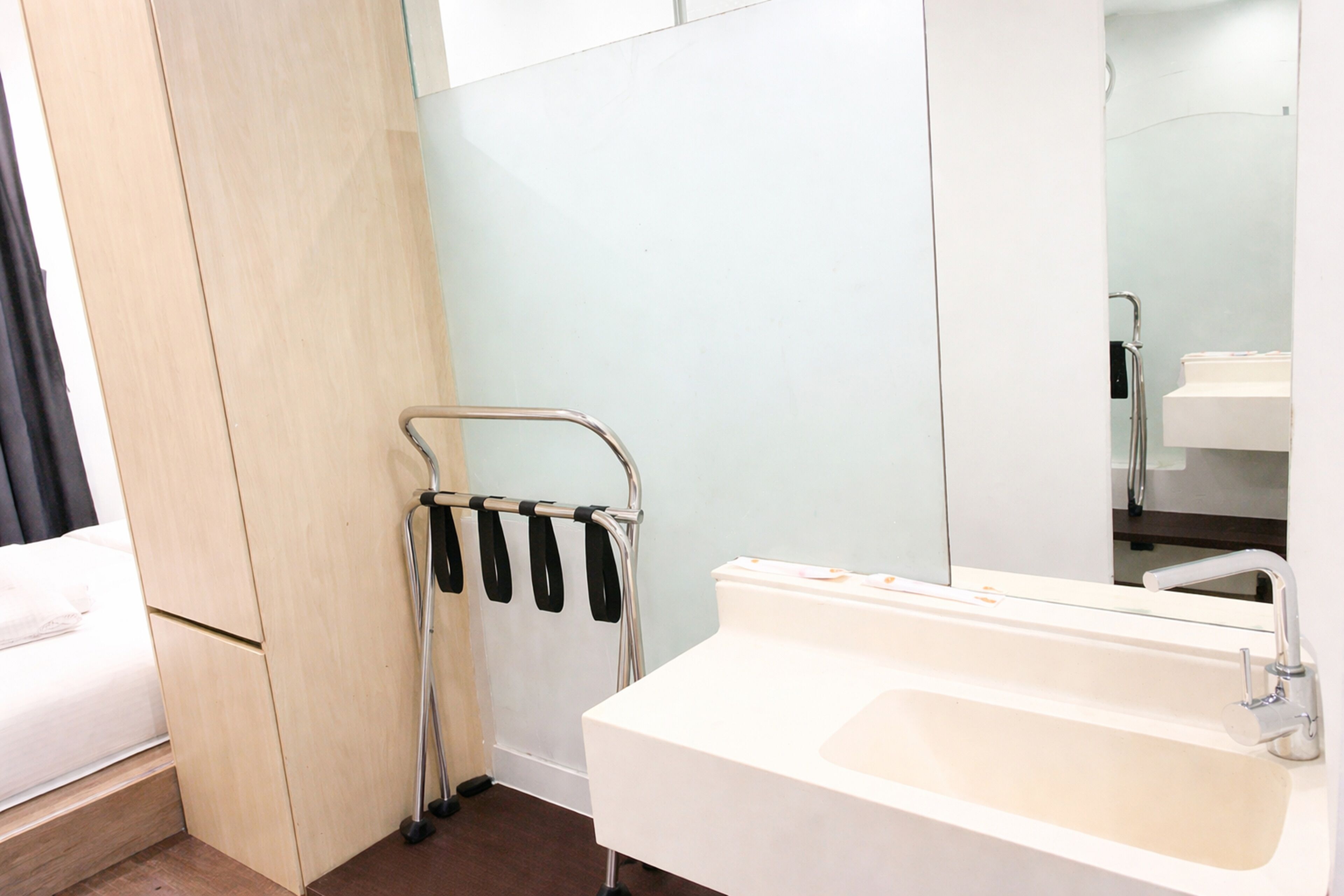 Un bagno d'albergo con un lavandino bianco, uno specchio e un portasciugamani.
