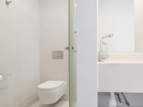 A modern bathroom with a toilet, a sink, and a mirror. - A Hotel Dickson (Singapore)