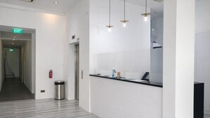 Un espace d’accueil moderne comprenant un comptoir de réception, une poubelle et un panneau indiquant la sortie.