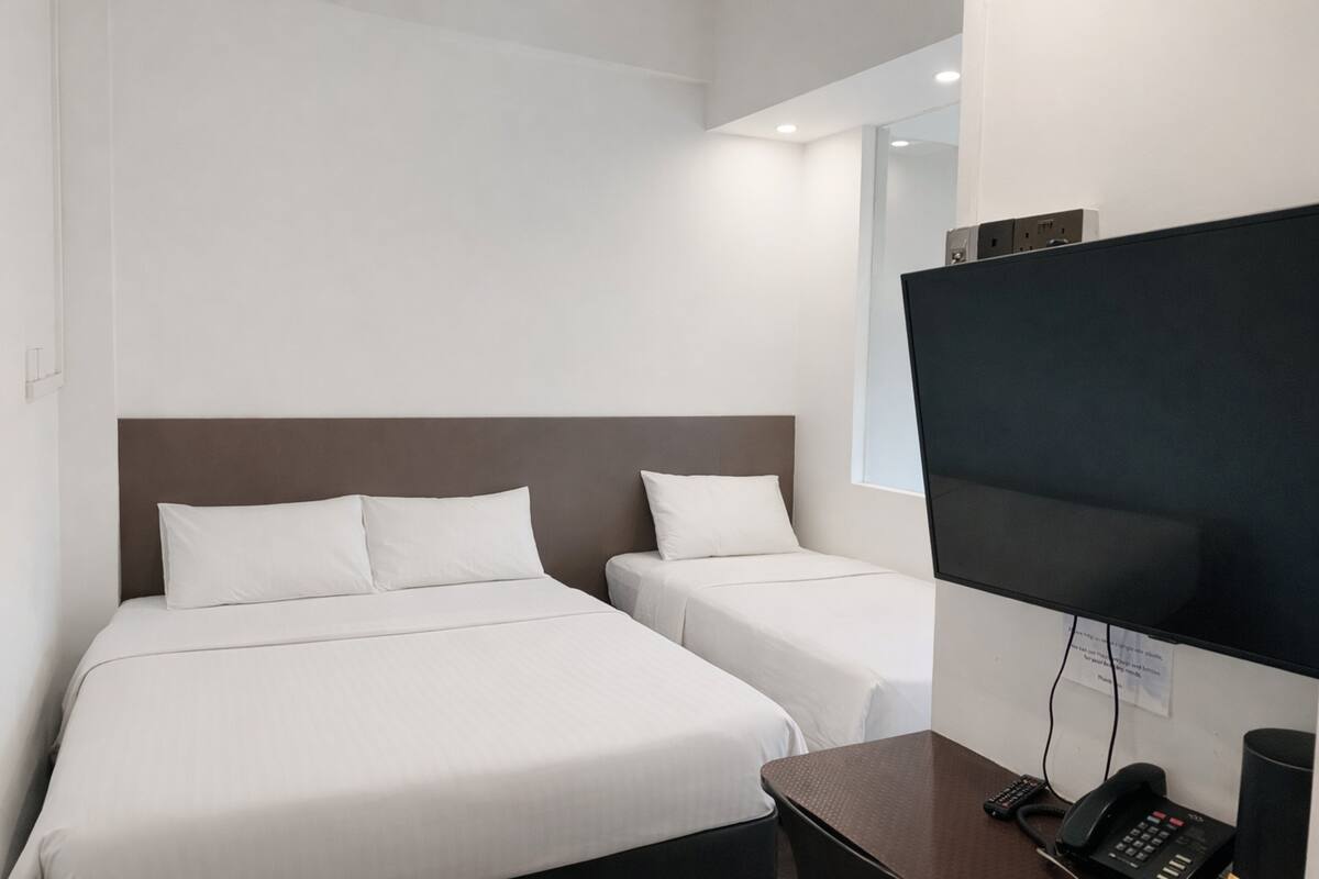 A hotel room with two beds, a desk with a phone, and a TV mounted on the wall.