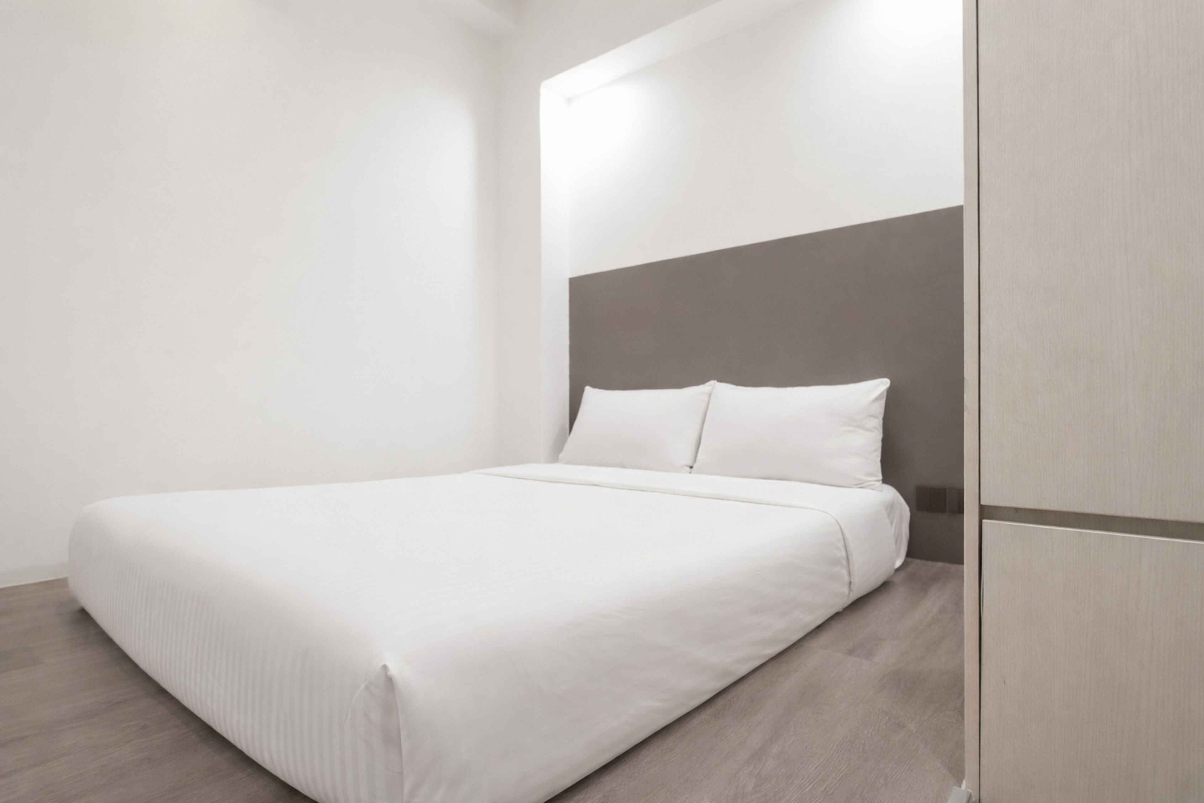Un dormitorio moderno con una cama grande, un cabecero de madera y un armario.
