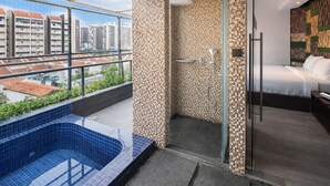 Une salle de bain moderne avec une douche à parois de verre, une baignoire aux carreaux bleus et une vue sur le paysage urbain.