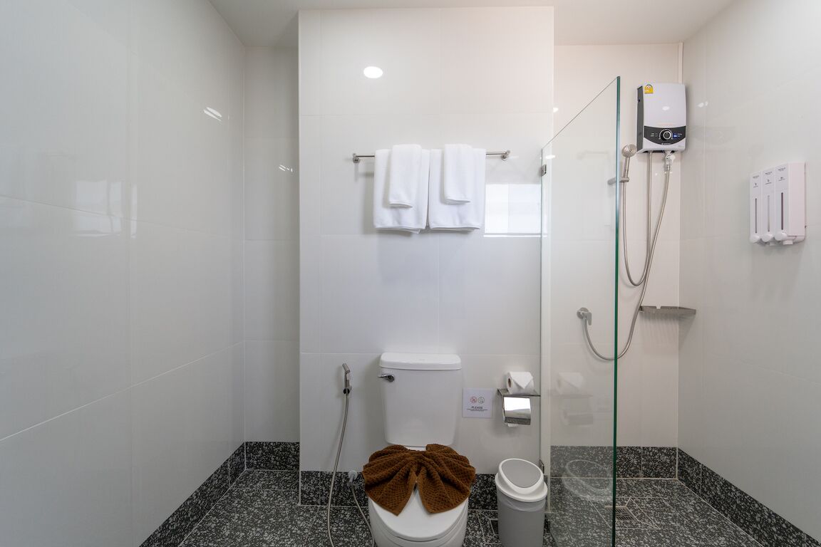 A modern bathroom with a toilet, a glass shower enclosure, and a towel rack.