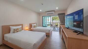 A hotel room with two beds, a TV, and a balcony with a table and chairs.