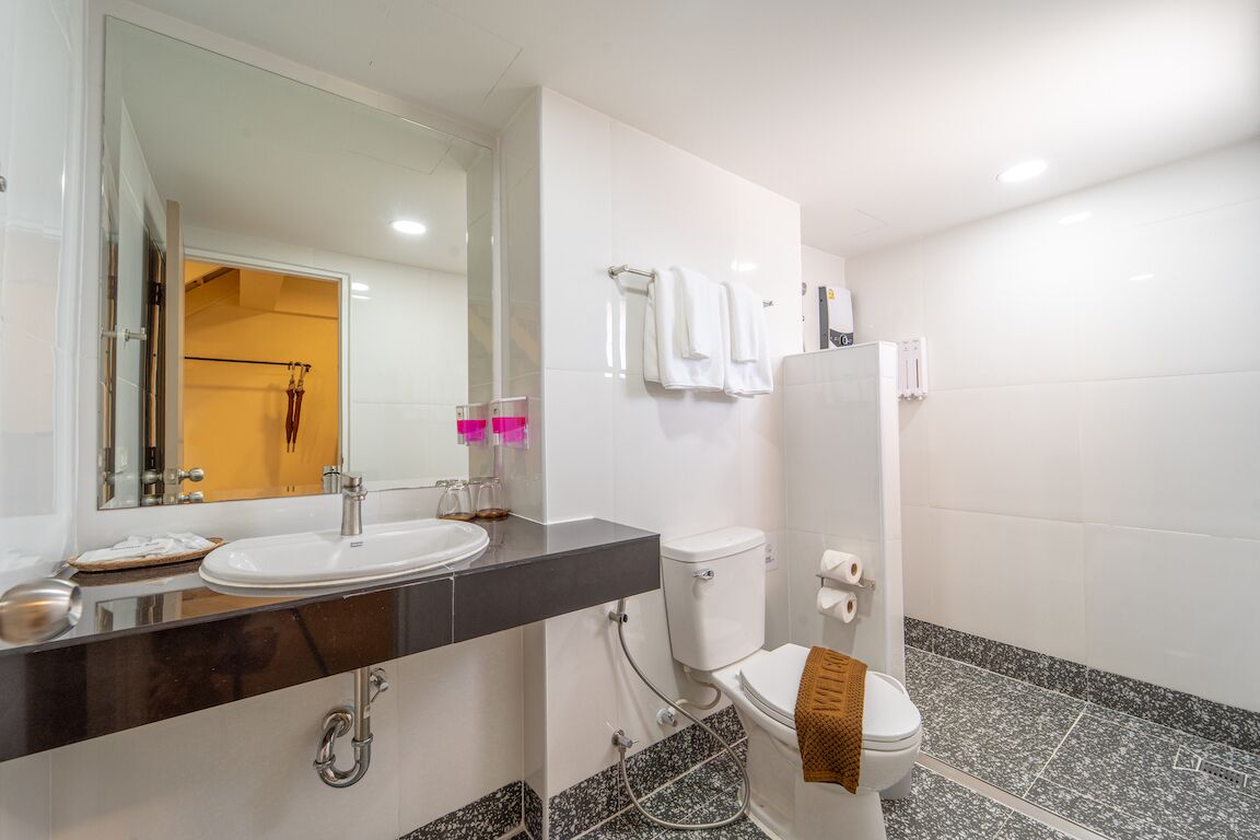 Un baño moderno con lavamanos blanco, inodoro y zona de ducha.