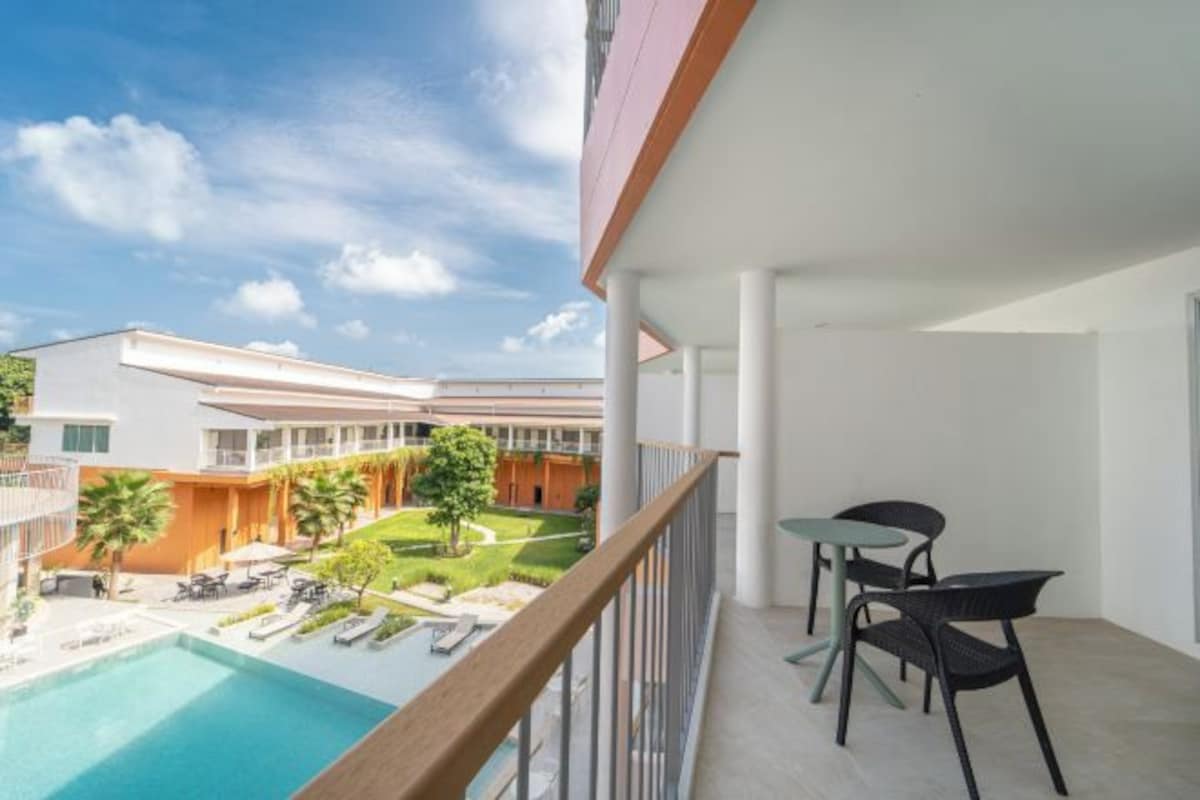 Un balcon avec vue sur la piscine, un espace salon extérieur et un ciel dégagé.