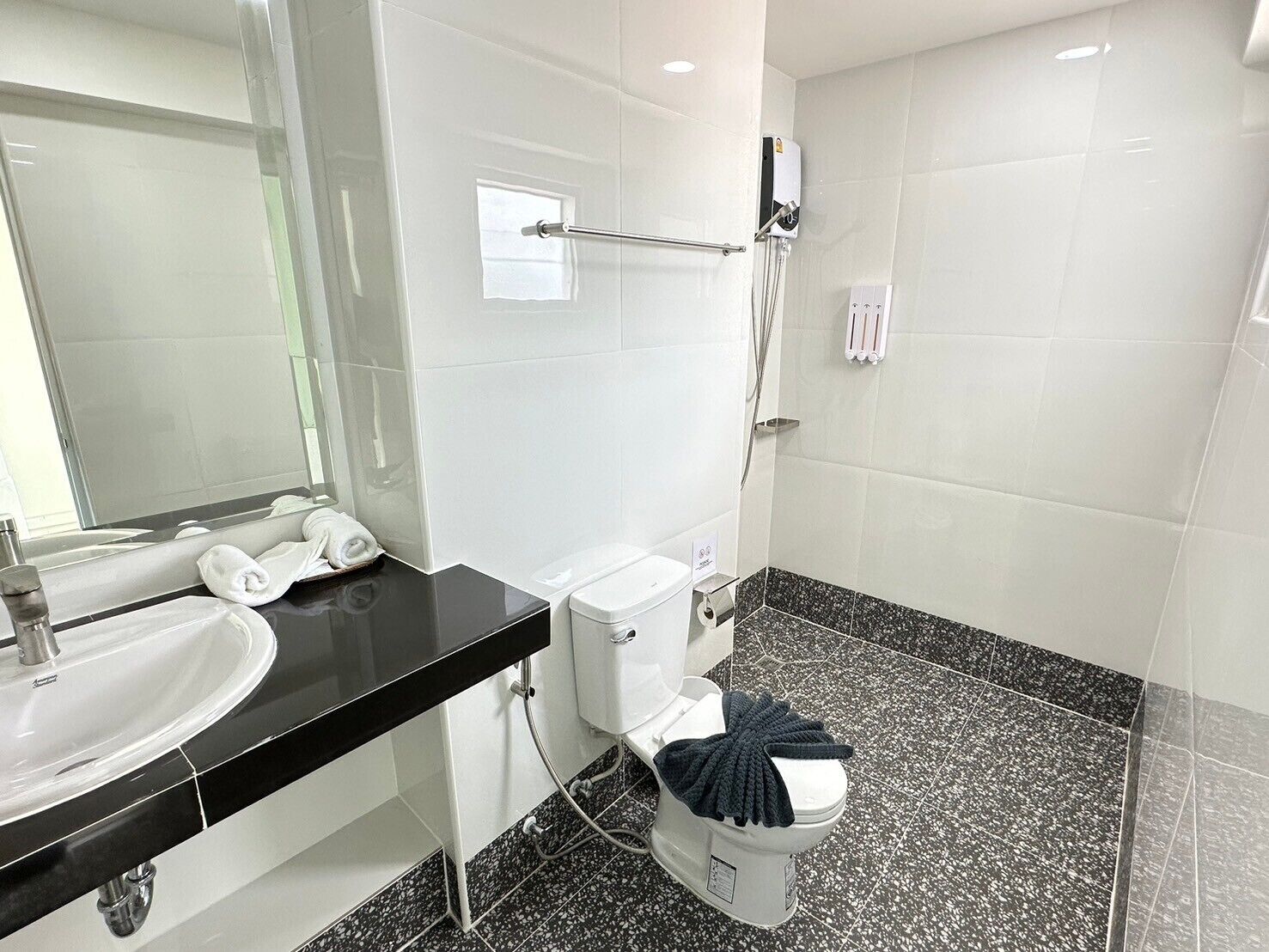 Un baño moderno con lavamanos de superficie negra, inodoro blanco y zona de ducha.