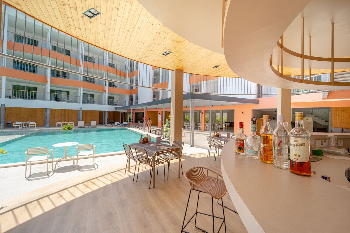 A modern hotel interior with a pool, bar area, and multiple floors with balconies.