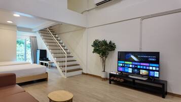 Una sala de estar moderna con una escalera, un televisor de pantalla plana, una planta en maceta y una mesa de centro de madera.