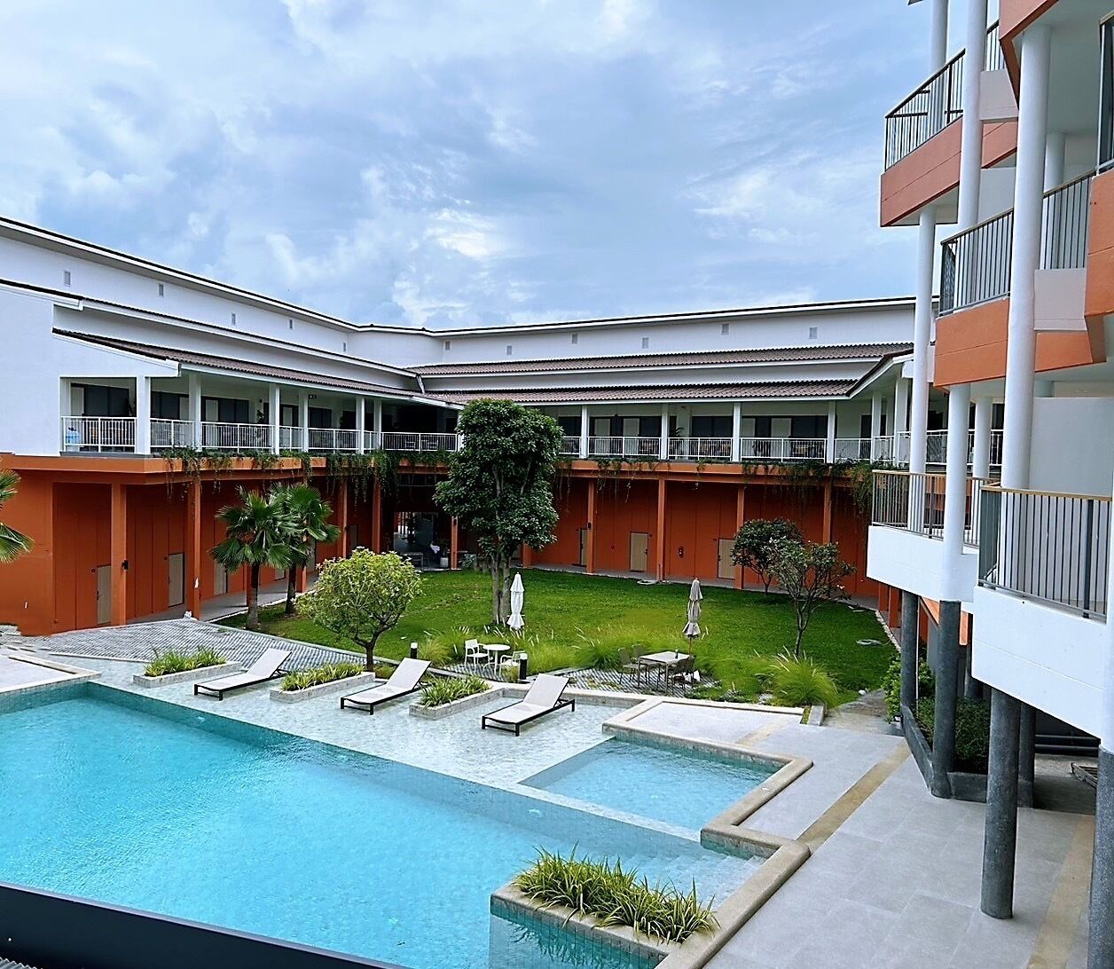 Un patio de hotel con piscina, varios balcones y abundante vegetación.