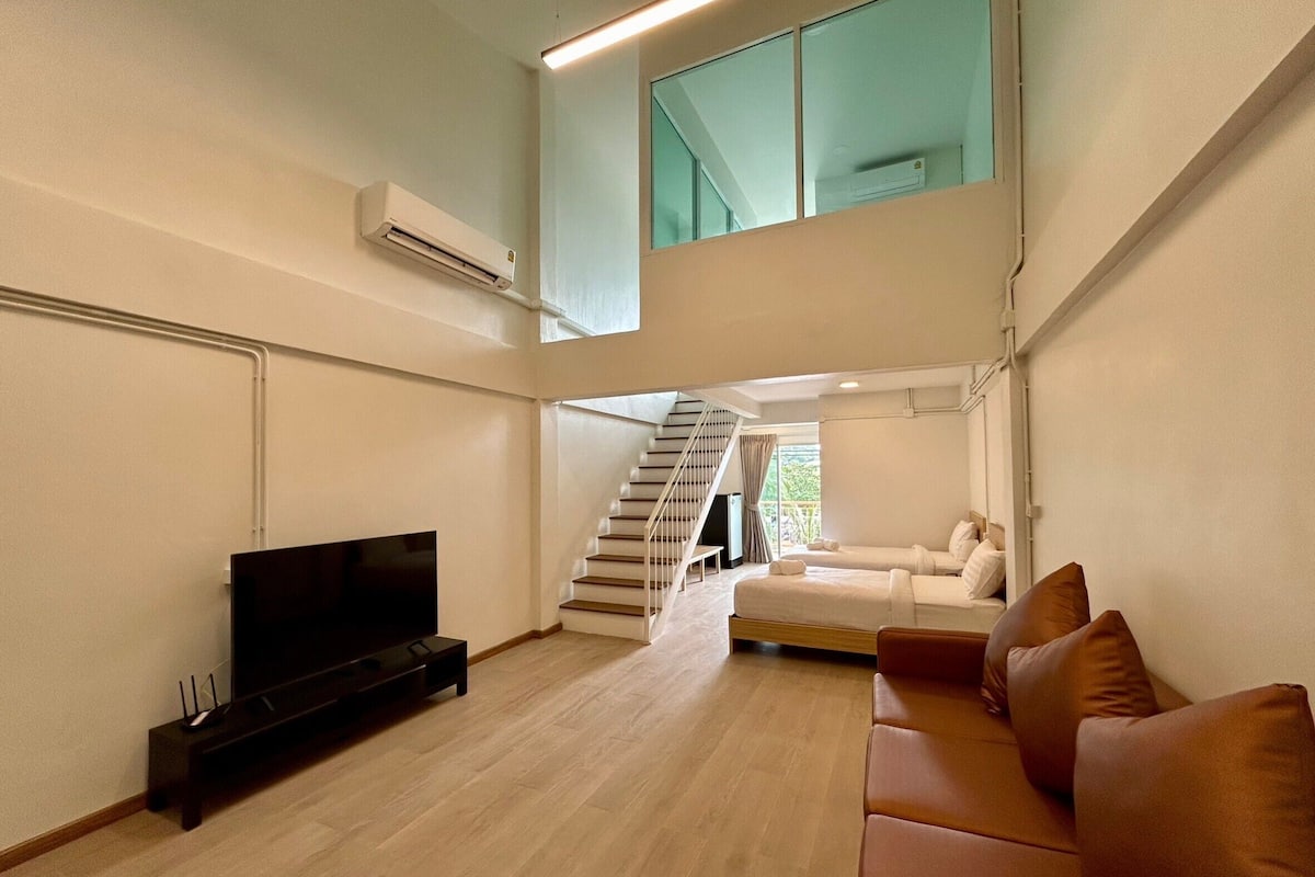 Uma sala de estar moderna com televisão de tela plana, uma escada que leva a um andar superior e um sofá branco.