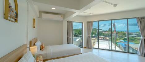 A hotel room with two beds, a large window with a view, and a ceiling fan.