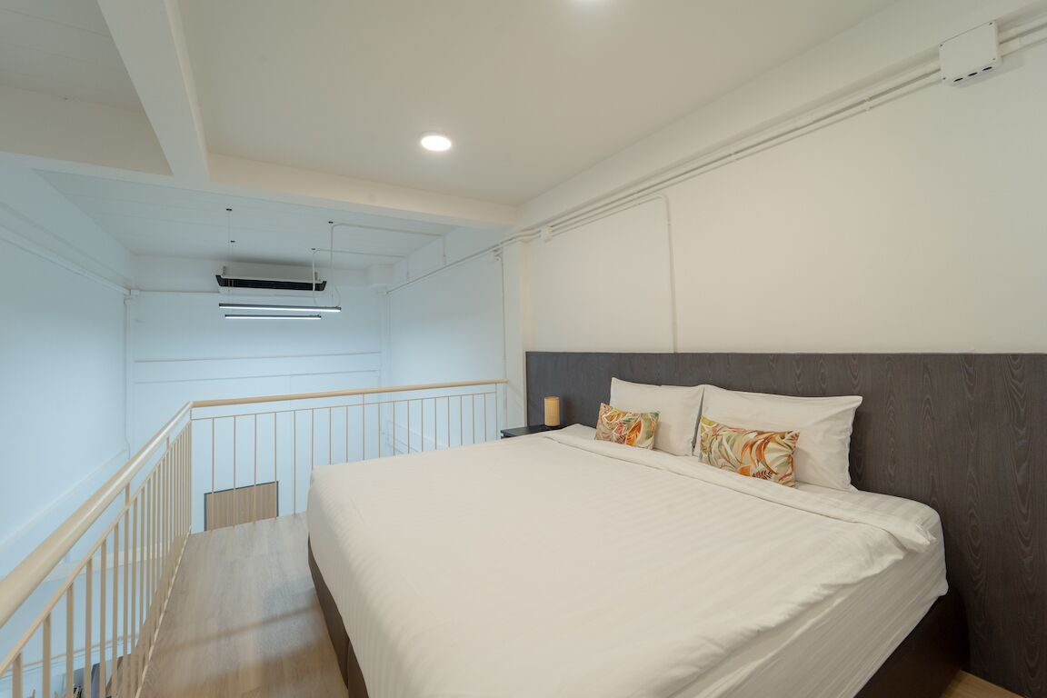 Un dormitorio con una cama grande, un cabecero y una escalera que lleva a un nivel superior.