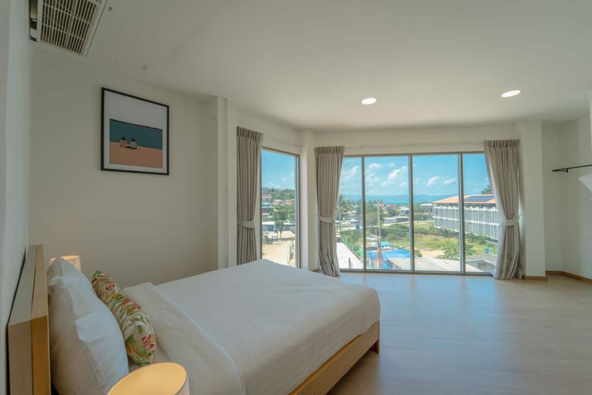 Um quarto espaçoso com uma cama grande, vista para um resort e uma varanda.