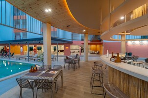 Un amplio espacio interior con piscina, zonas de estar y una recepción.