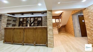 A spacious room with a wooden counter and shelving, a staircase, and a brick wall. - Dreamvilla tbilisi (Tbilisi)
