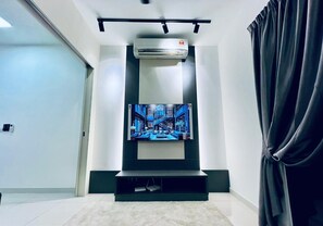 Relax in this stylish living room with a flat-screen TV and ceiling-mounted air conditioning unit.